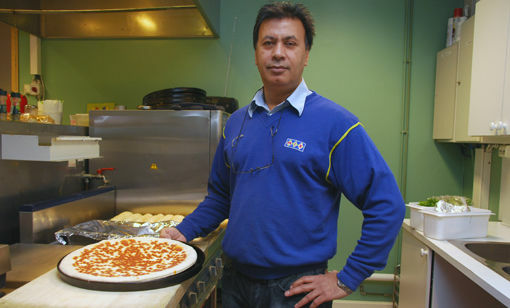 Mazhar hiver seg fort rundt og lager en god pizza til sultne salangsværinger. FOTO: KARIN SWART-DONDERS