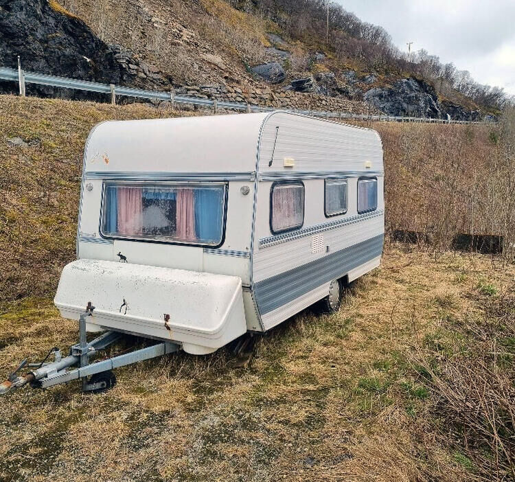 Denne campingvogna har stått forlatt på rasteplassen ved Mjøsundbrua på Ibestad- siden i snart ett år nå. Nå etterlyser kommunen eieren.