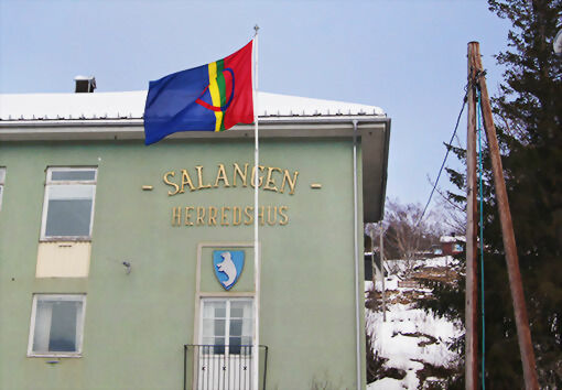 I toppen av flaggstangen utenfor Herredshuset på Sjøvegan svaier i dag det samiske flagget. Det er samenes nasjonaldag, noe som markeres hele Norge, i tillegg til de tre andre land. Her i distriktet er det i Lavangen at den største markeringen finner sted. FOTO: KNUT-ARILD JOHANSEN